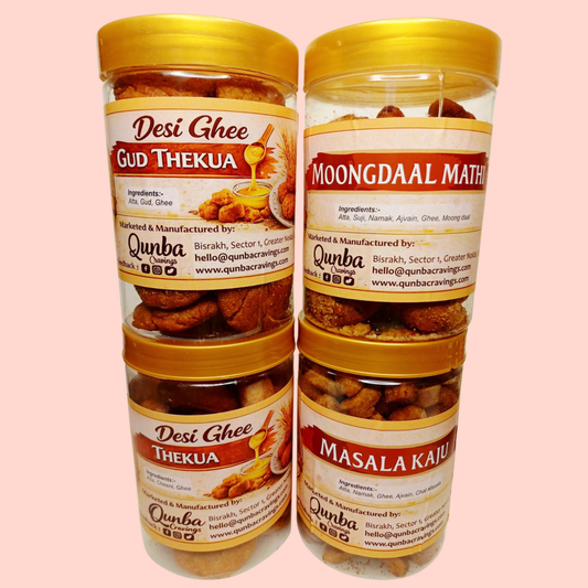 Two transparent snack jars from Qunba Cravings placed side by side, one containing traditional Thekua and the other Moong Daal Matthi, both with red lids and ornate cream-and-gold stickers featuring the Qunba Cravings logo, family illustration, product names, and homemade Indian snack branding.